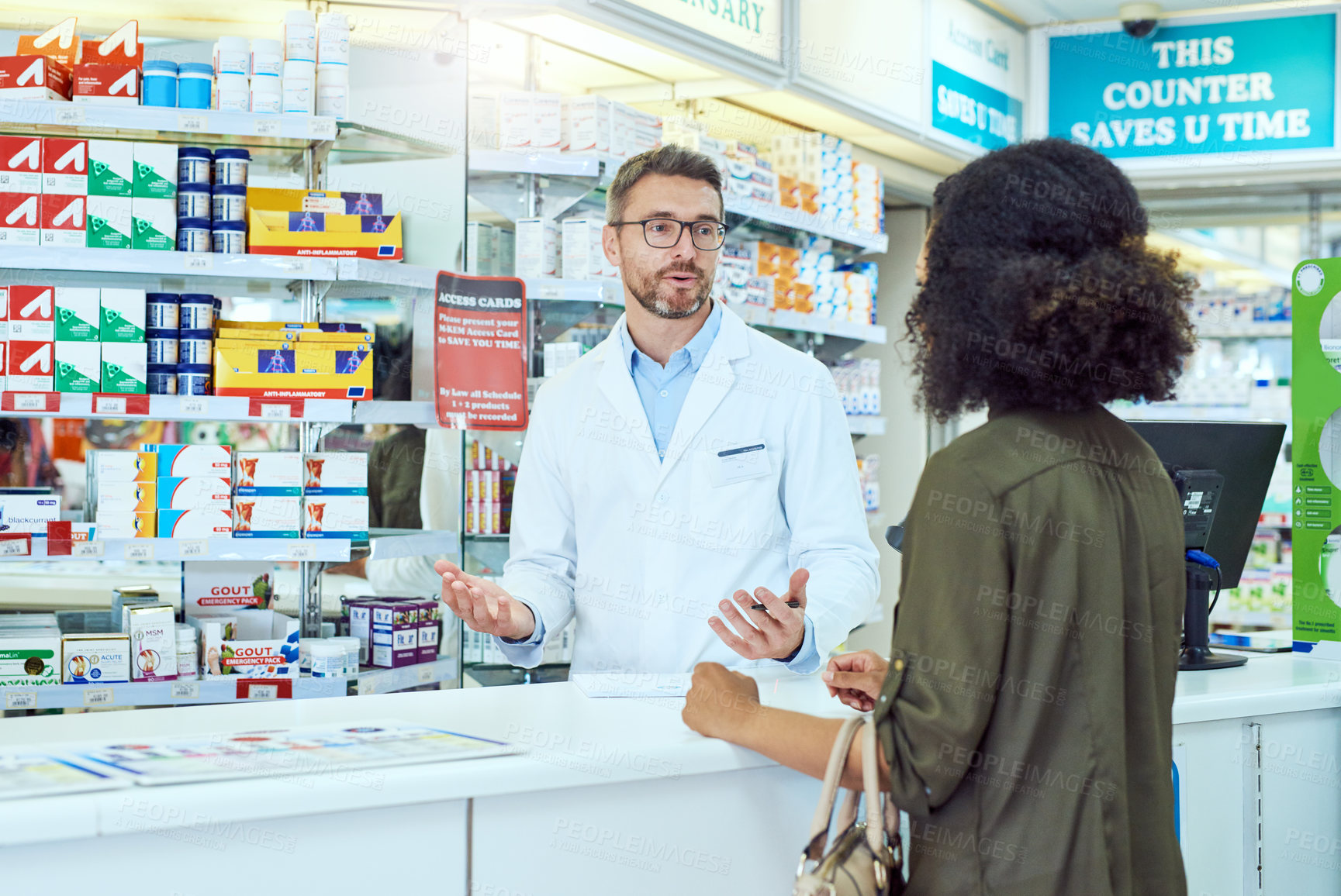Buy stock photo Cropped shot of a handsome mature male pharmacist helping a female customer in the pharmacy