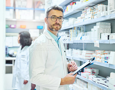 Buy stock photo Shot of a mature man doing inventory in a pharmacy with his colleague in the background
