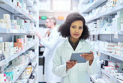 Buy stock photo Shot of a young woman using a digital tablet to do inventory in a pharmacy