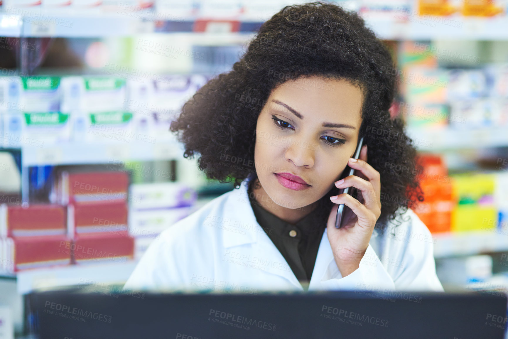 Buy stock photo Shot of a young woman using a computer and mobile phone at the counter of a pharmacy