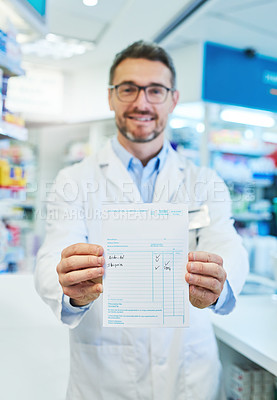 Buy stock photo Shot of a pharmacist holding up a prescription