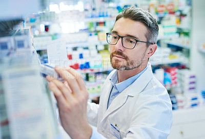 Buy stock photo Mature man, pharmacist and checking inventory with box for medical supplies, stock or medication at pharmacy. Male person or healthcare employee reading pharmaceuticals or drugs at dispensary store