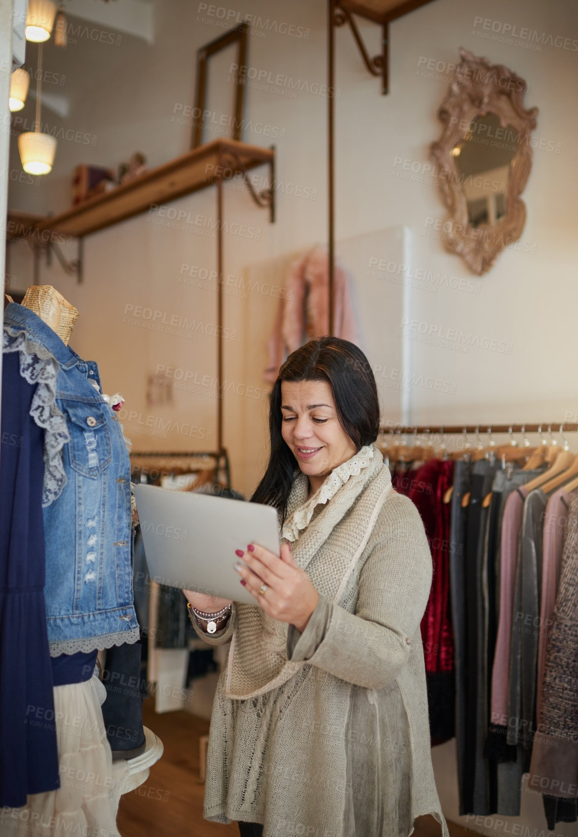 Buy stock photo Cropped shot of an attractive mature female entrepreneur working on a tablet in her self-owned boutique