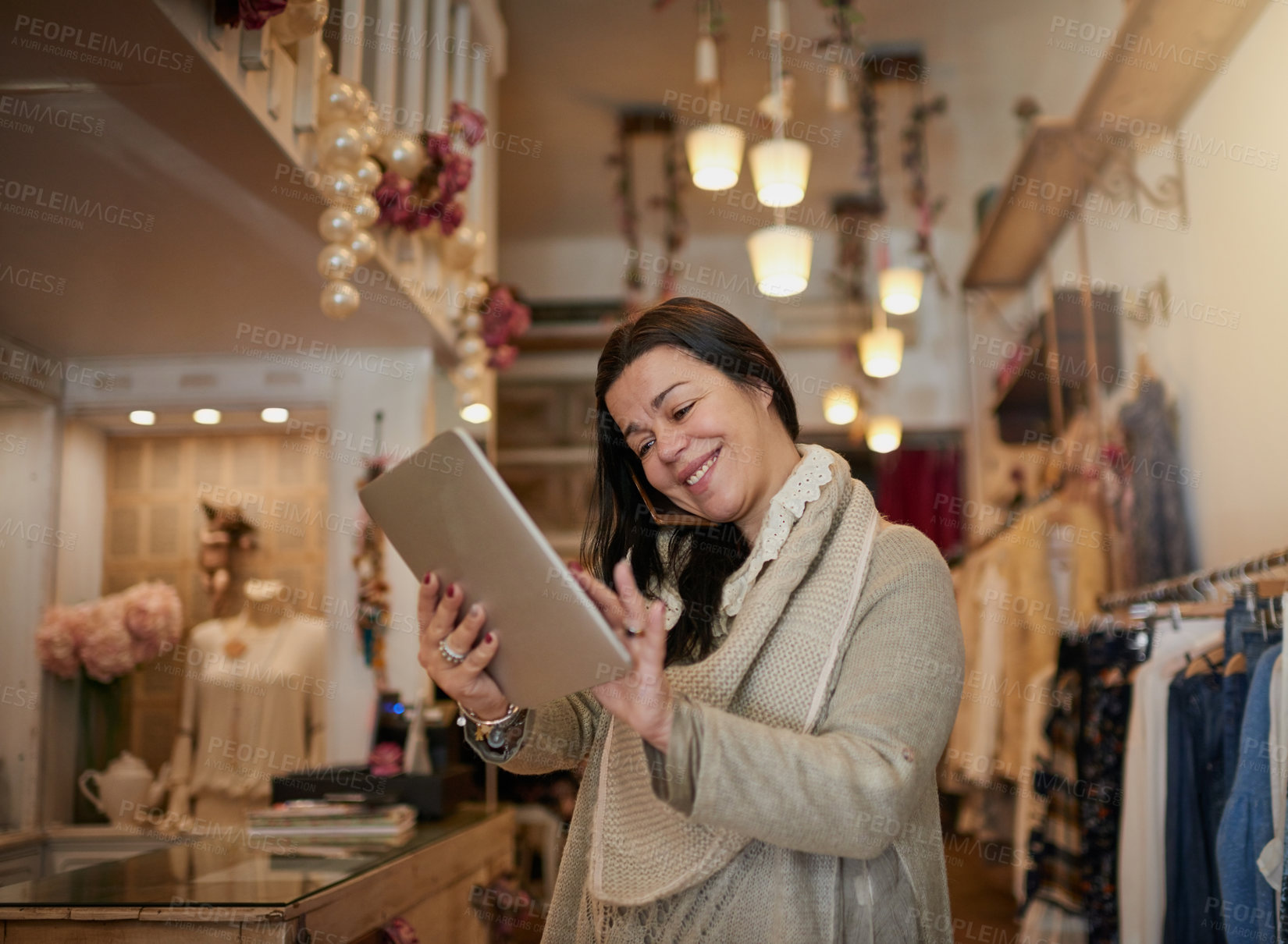 Buy stock photo Cropped shot of an attractive mature female entrepreneur working on a tablet in her self-owned boutique