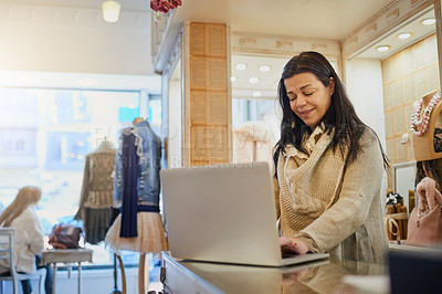Buy stock photo Cropped shot of an attractive mature female entrepreneur working on a laptop in her self-owned boutique