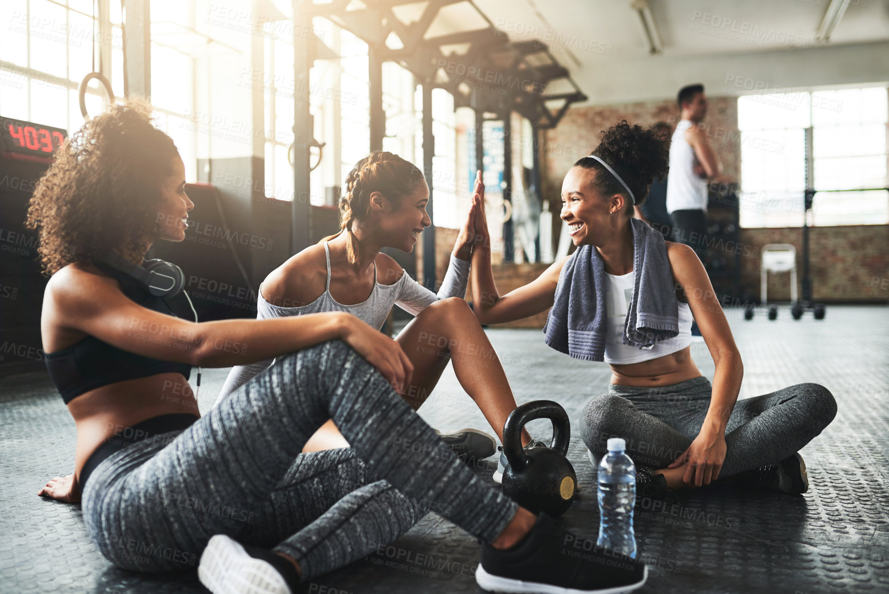 Buy stock photo Shot of young women giving each other a high five while taking a break at the gym