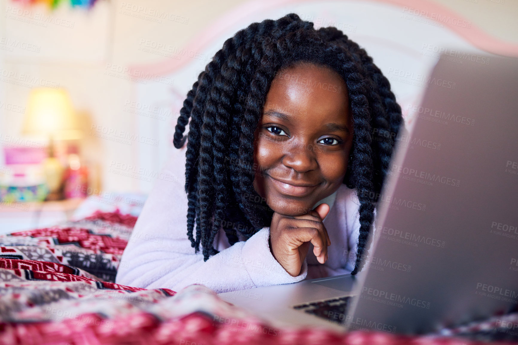 Buy stock photo Shot of an adorable little girl using a laptop while lying on her bed in her bedroom
