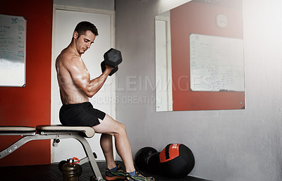 Buy stock photo Full length shot of a handsome and muscular young man working out with a dumbbell in the gym