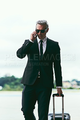 Buy stock photo Cropped shot of a handsome mature businessman walking with his luggage outside of the airport