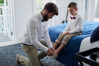 Buy stock photo Cropped shot of a young handsome father helping his adorable son put on his shoes at home