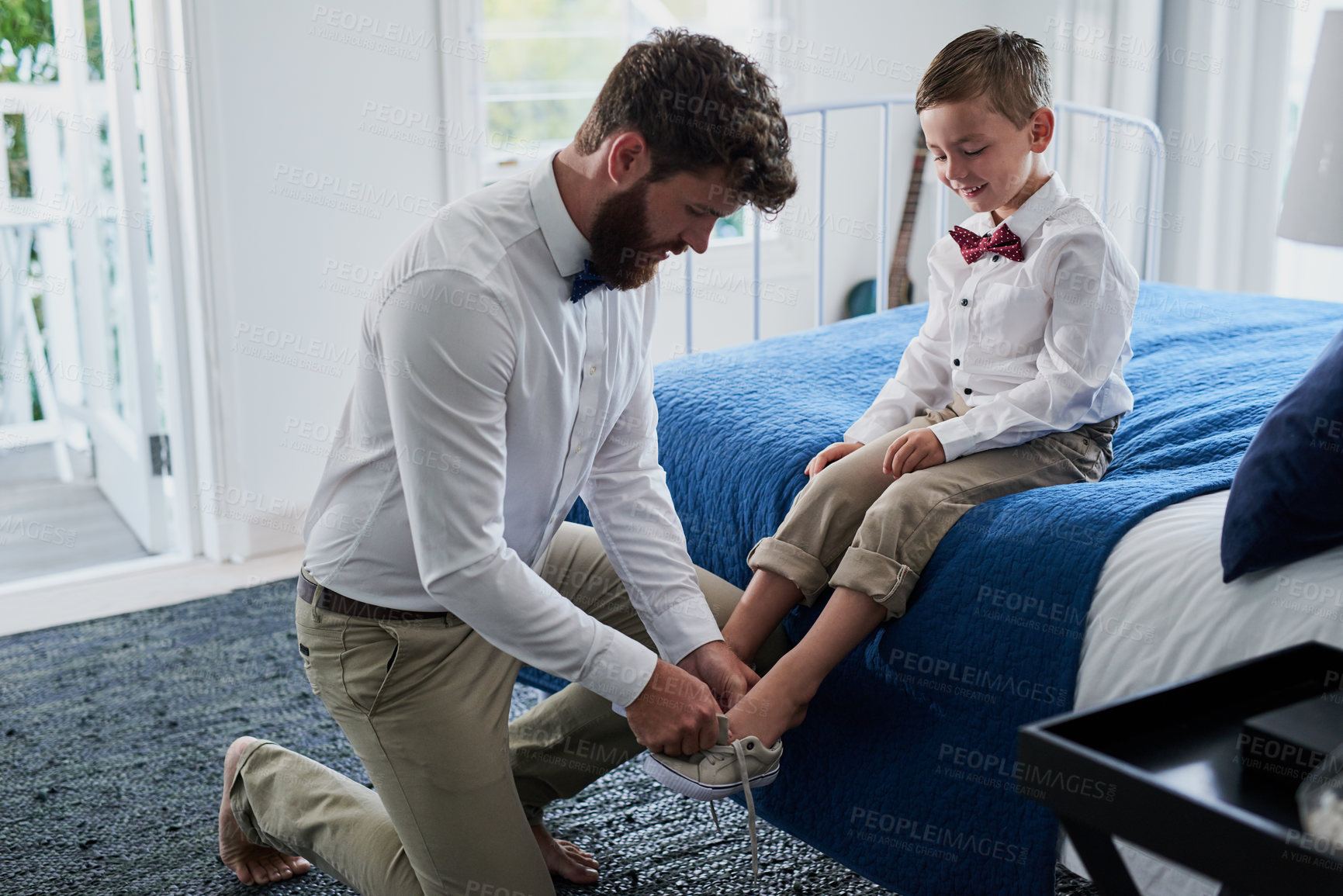 Buy stock photo Cropped shot of a young handsome father helping his adorable son put on his shoes at home