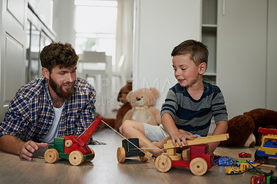 Buy stock photo Shot of a handsome young man and his son playing with toys on the bedroom floor