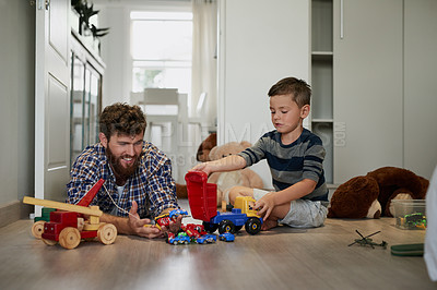 Buy stock photo Shot of a handsome young man and his son playing with toys on the bedroom floor