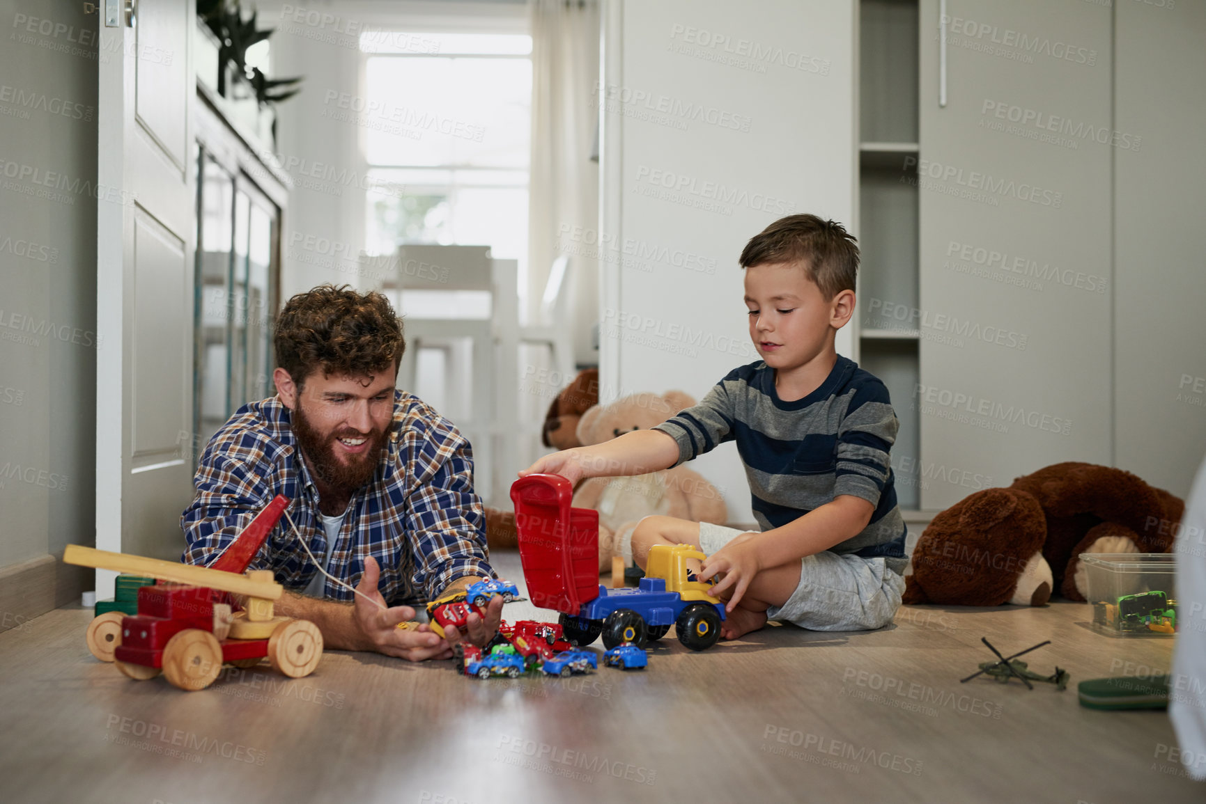 Buy stock photo Shot of a handsome young man and his son playing with toys on the bedroom floor