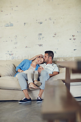 Buy stock photo Shot of a young married couple being affectionate on the sofa at home