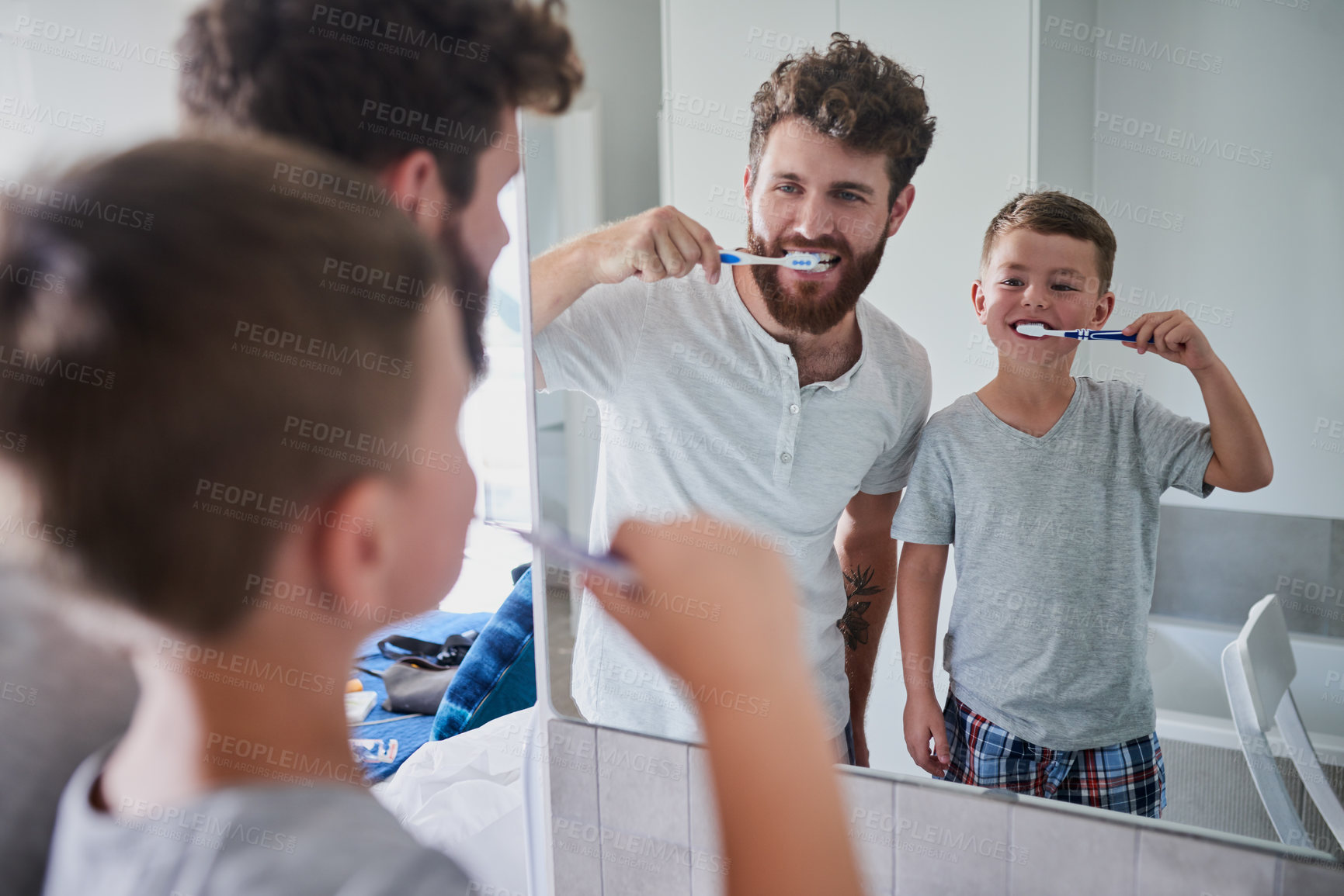 Buy stock photo Shot of a father and his little son brushing their teeth together in the bathroom at home