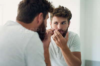 Buy stock photo Cropped shot of a handsome young man checking out his skin in the bathroom mirror