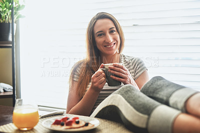 Buy stock photo Cropped shot of a young woman having breakfast and chilling by the dining table in the morning at home