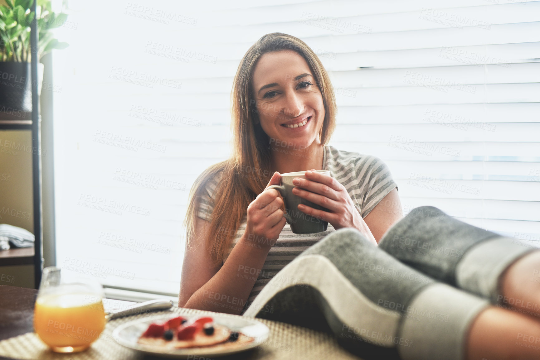 Buy stock photo Cropped shot of a young woman having breakfast and chilling by the dining table in the morning at home