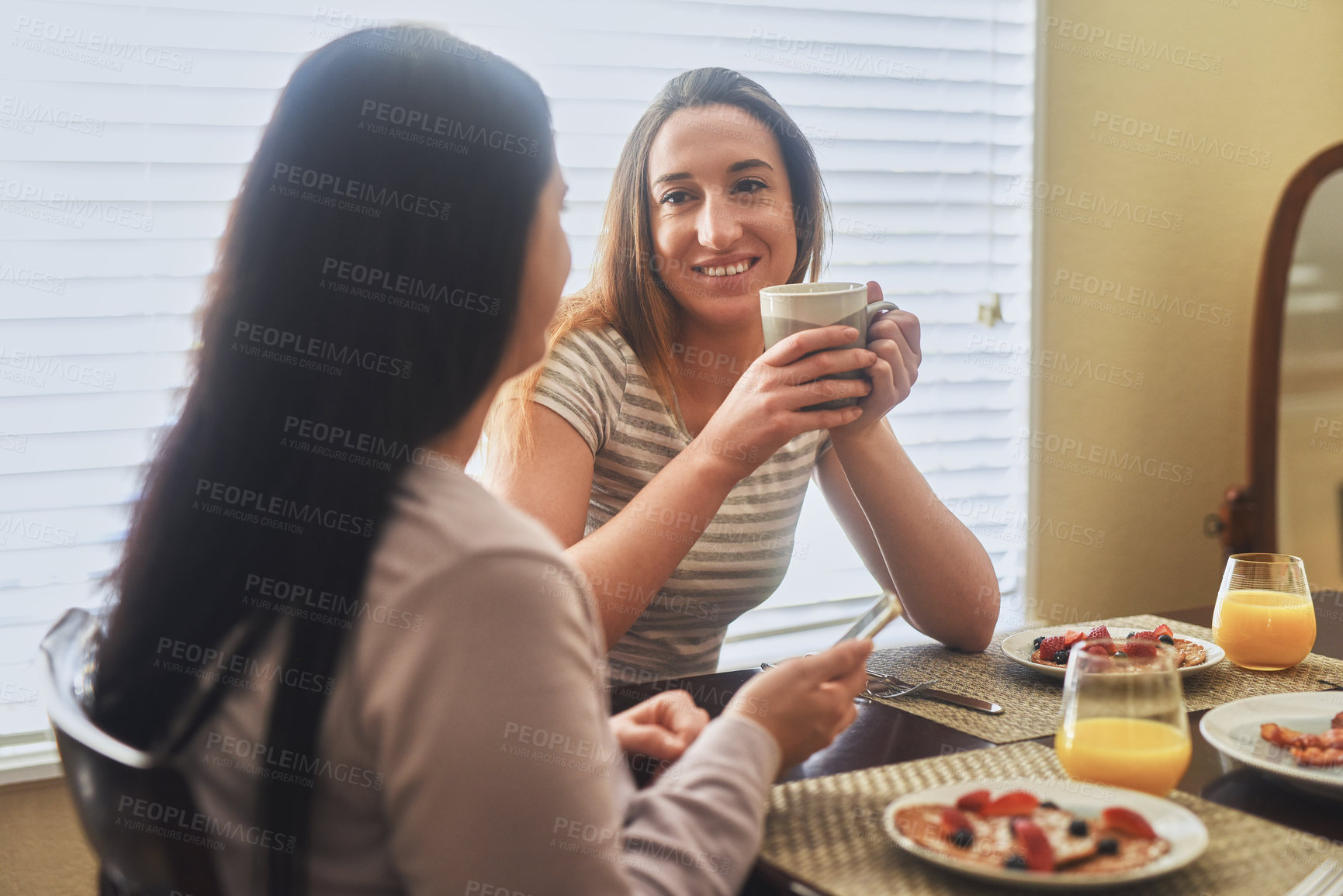 Buy stock photo Cropped shot of two young women having breakfast in the morning at home