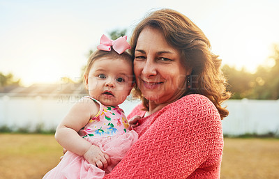 Buy stock photo Portrait of a grandmother holding her adorable little baby granddaughter in the backyard at home