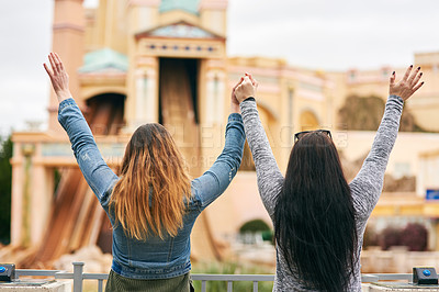 Buy stock photo Rearview shot of two unrecognizable female best friends at an amusement park outside