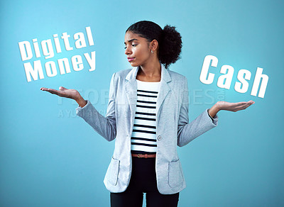 Buy stock photo Studio shot of an attractive young woman weighing up her monetary options against a blue background