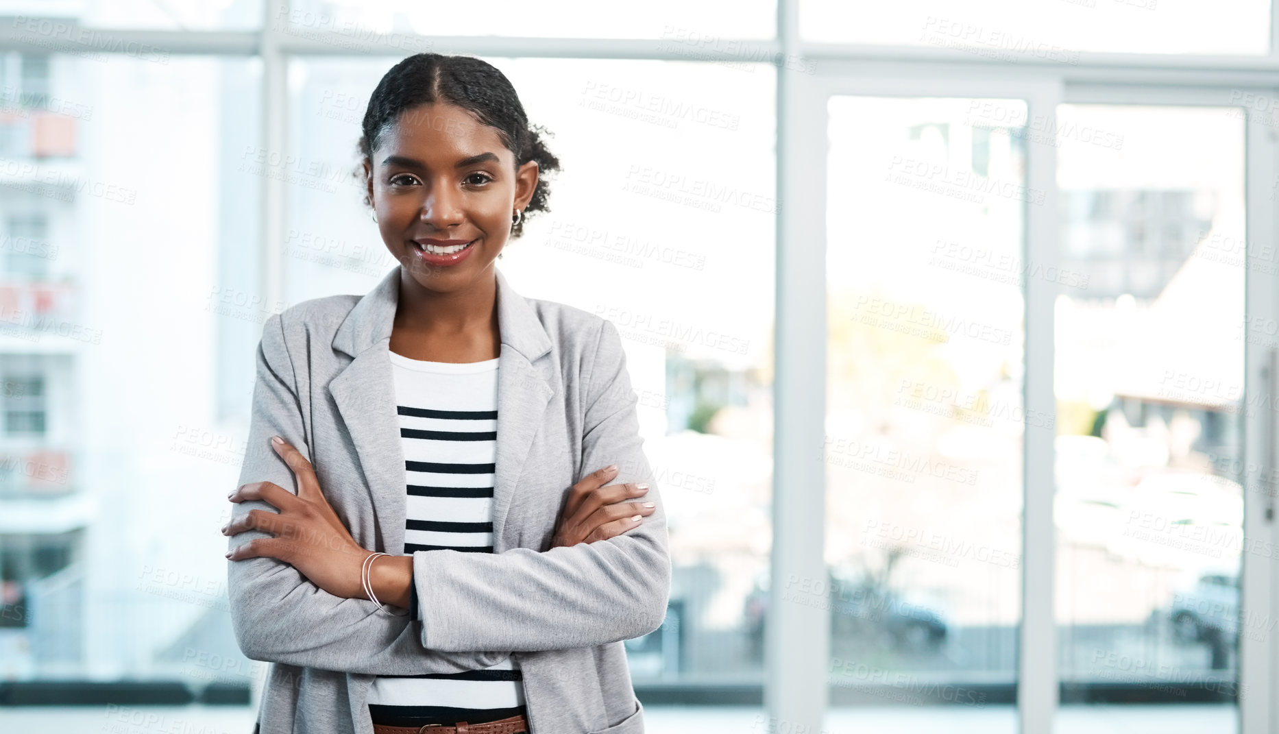 Buy stock photo Business woman standing with arms crossed, looking proud and confident in an office alone at work. Portrait of a young black female manager, boss or employee smiling, looking successful and powerful