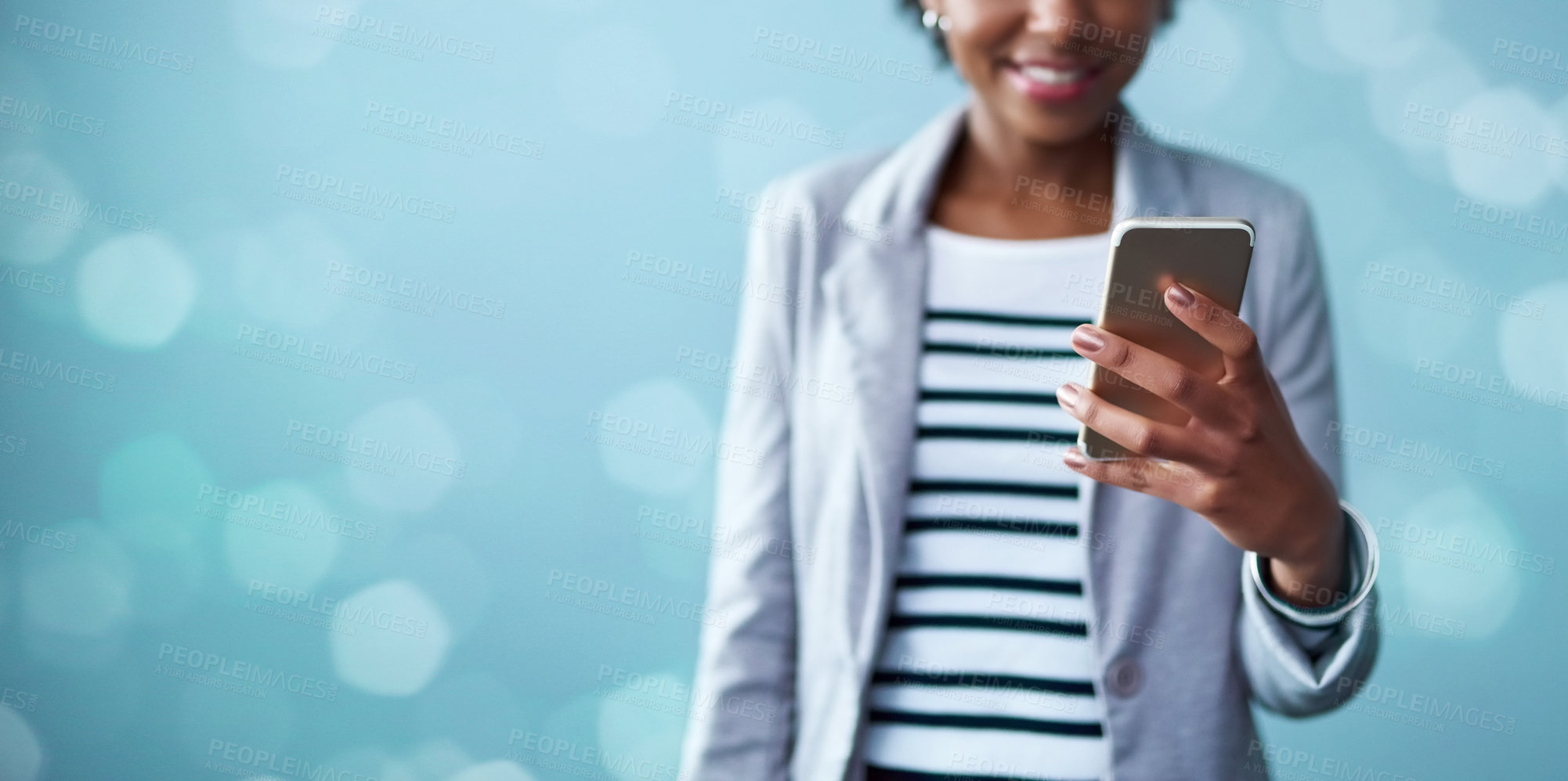 Buy stock photo Cropped studio shot of a young businesswoman using a mobile phone against a blue background