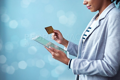 Buy stock photo Credit card for online banking, shopping and buying on tablet while standing alone isolated on blue copy space. African female paying for purchase with fintech technology on blue bokeh background