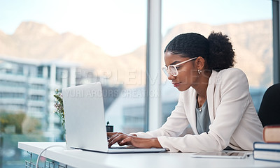 Buy stock photo Data professional and secretary typing an email on a laptop and doing online research while working in an office. African entrepreneur looking focused while using the internet for work