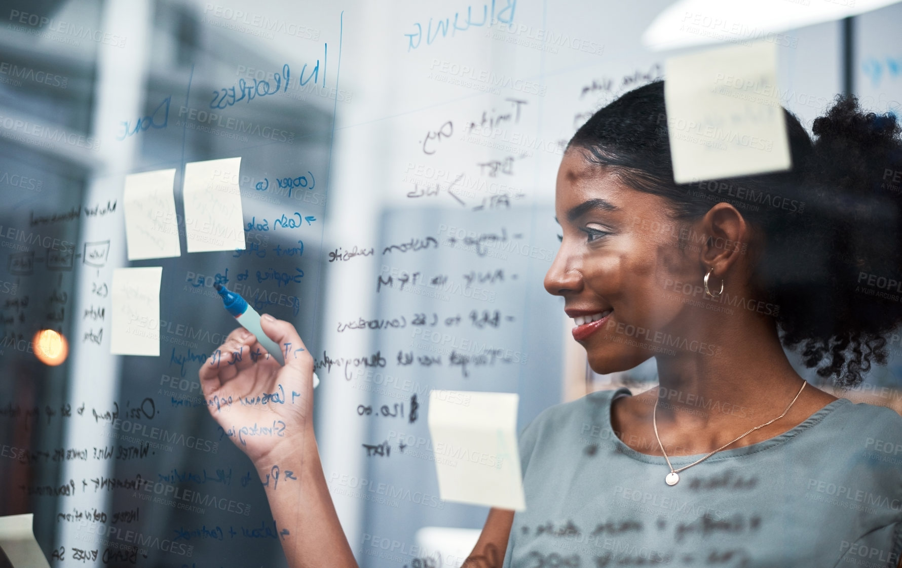 Buy stock photo Female entrepreneur planning an innovative strategy on a glass wall in a corporate office. Happy, confident and successful corporate woman brainstorming ideas for the company's progress at a company