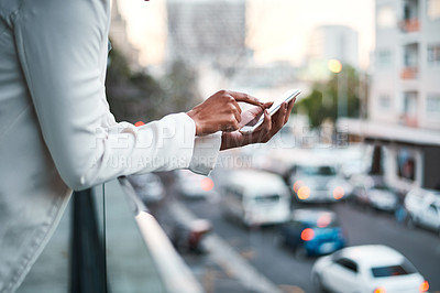 Buy stock photo Businessperson texting on their mobile phone to send an email outside on the balcony of a modern office, overlooking a busy city. Corporate professional worker typing outdoors to send a text message