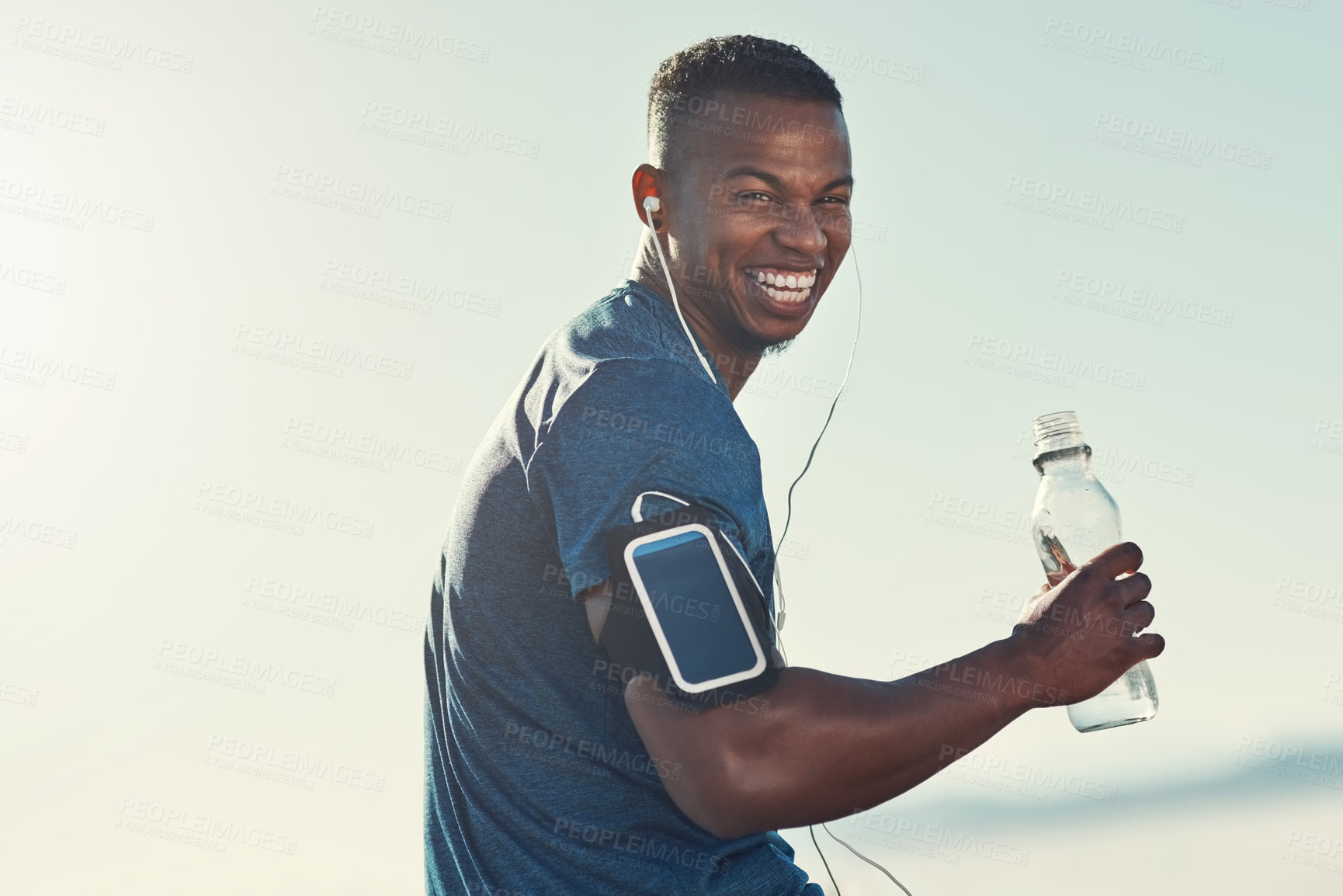 Buy stock photo Black man, drink water and portrait in outdoors for running, thirst and hydrate on sports break. Person, blue sky and mineral liquid in bottle for nutrition, music and phone app for streaming song