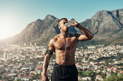 Buy stock photo Cropped shot of a handsome young male runner taking a break and drinking water outdoors