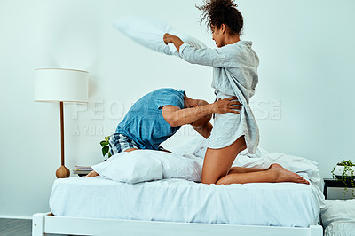 Buy stock photo Couple, play and pillow fight on bed, funny and relax with bonding for love, care and connection in home. Man, woman and attack with comic games, excited and laugh together in morning at apartment