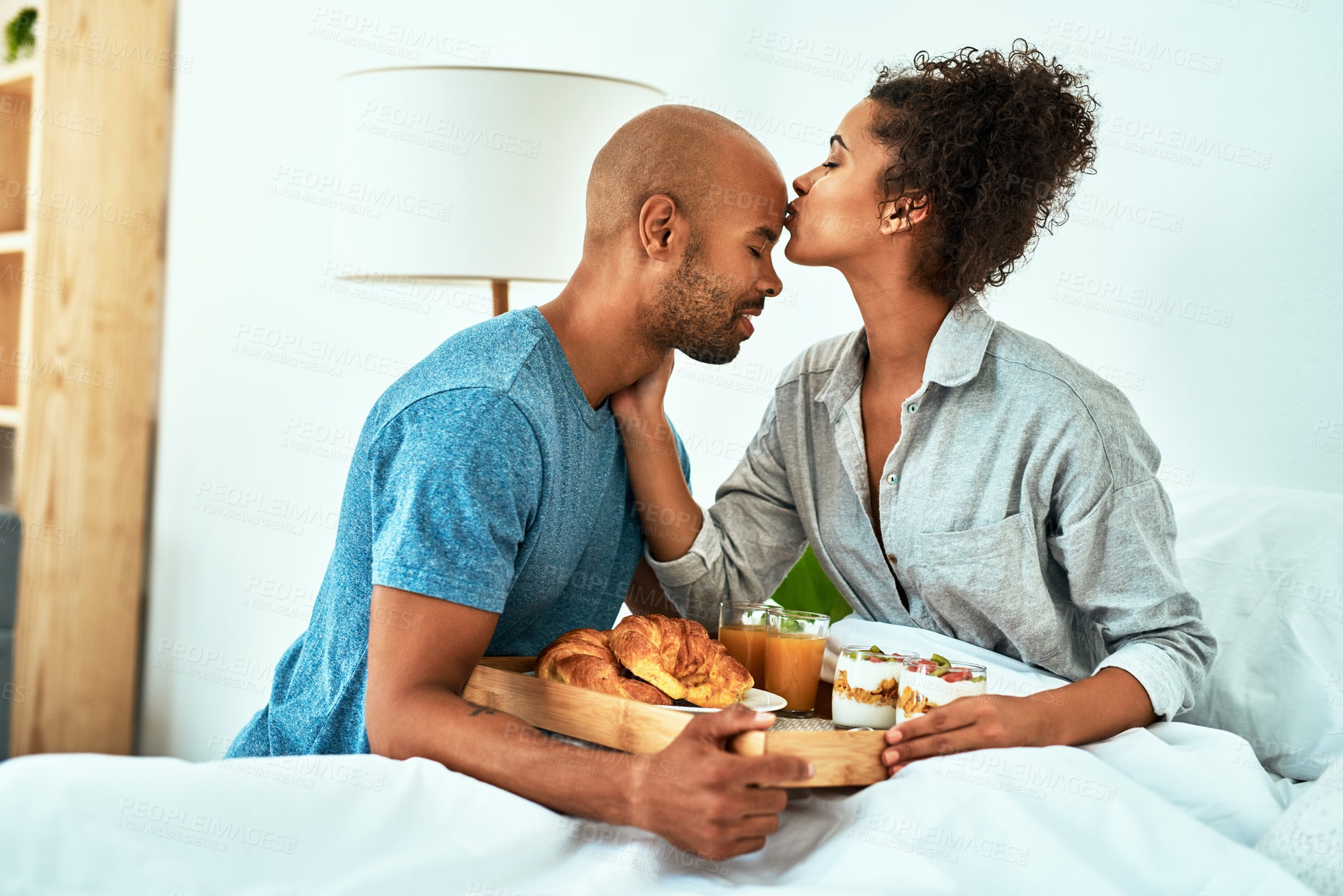 Buy stock photo Cropped shot of an affectionate young couple having breakfast in bed