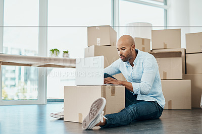 Buy stock photo Shot of a young man using a laptop while moving house