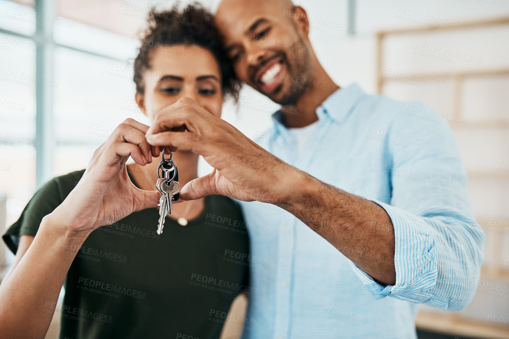 Buy stock photo Shot of a young couple holding the keys to their new home