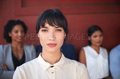 Buy stock photo Portrait of a young businesswoman standing outside with her colleagues in the background