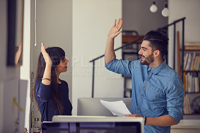 Buy stock photo Shot of a young businessman and businesswoman giving each other a high five in a modern office