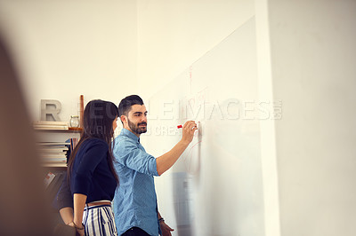 Buy stock photo Shot of a young businessman and businesswoman having a brainstorming session on a wall in a modern office