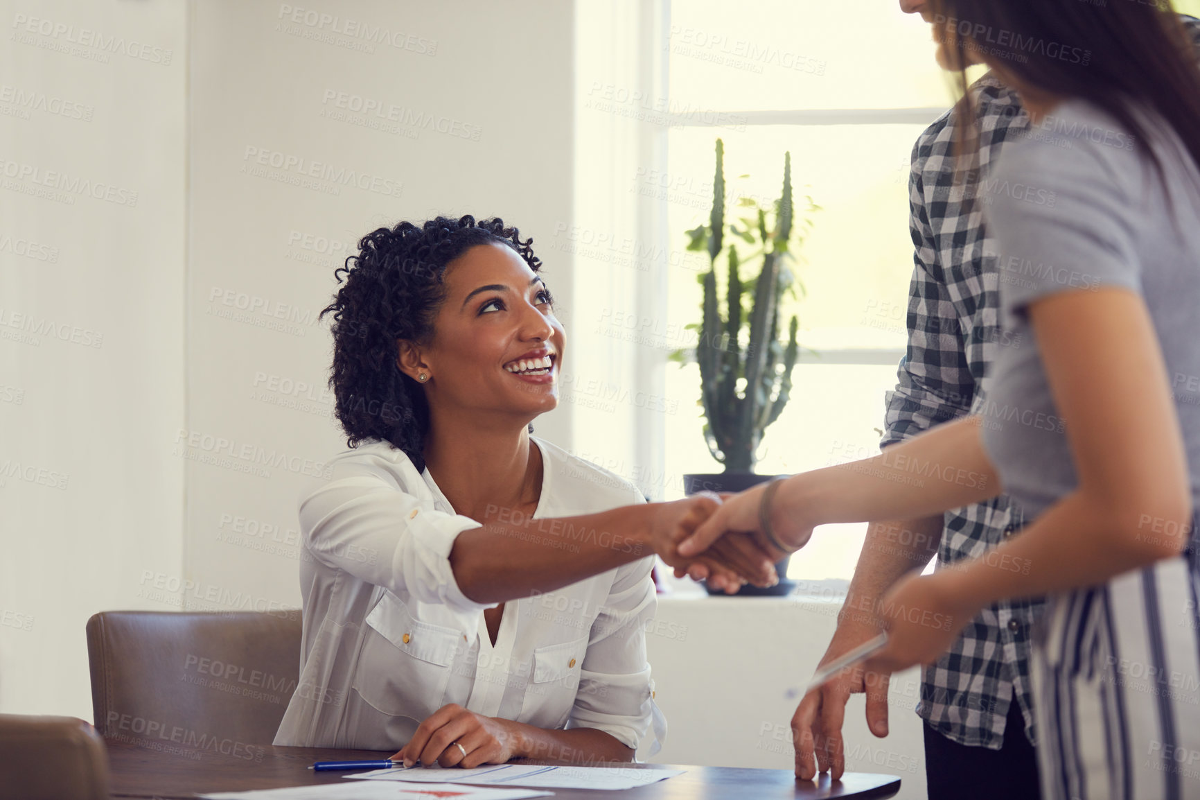 Buy stock photo Shot of two young businesswomen shaking hands in a modern office