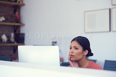 Buy stock photo Shot of a young businesswoman looking serious while using a computer in a modern office
