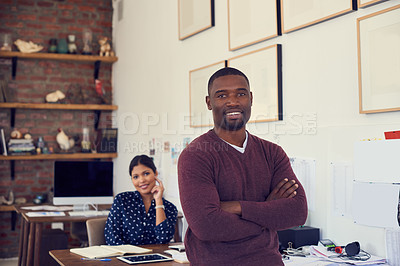 Buy stock photo Portrait of a confident young businessman working in a modern office with his colleague in the background