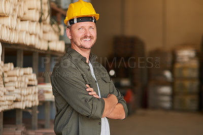 Buy stock photo Cropped portrait of a handsome mature construction worker standing with his arms folded in an industrial warehouse