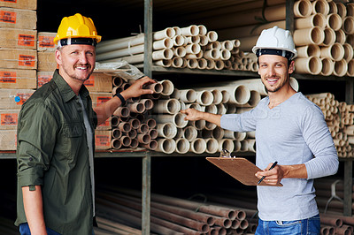 Buy stock photo Cropped portrait of two male construction workers looking over some paperwork while standing in an industrial warehouse