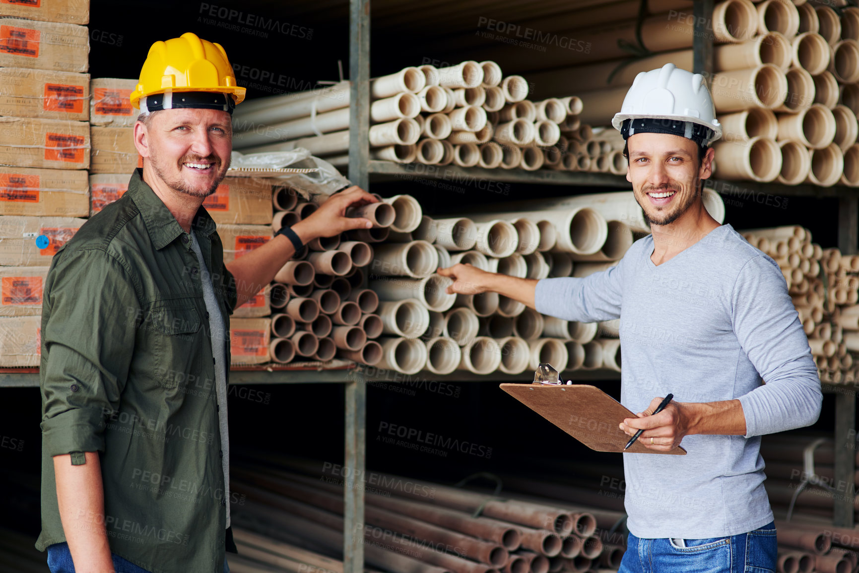 Buy stock photo Cropped portrait of two male construction workers looking over some paperwork while standing in an industrial warehouse