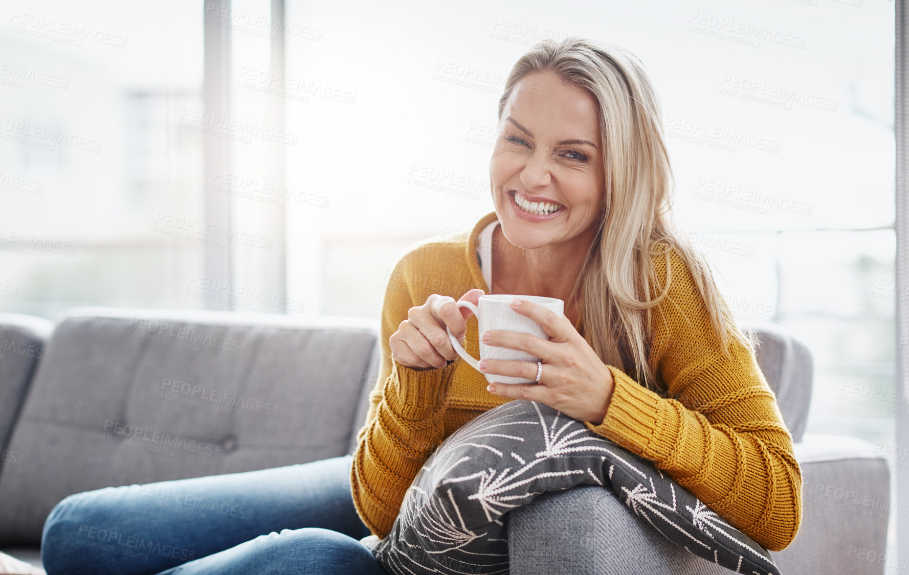 Buy stock photo Portrait of an attractive mature woman enjoying a beverage while relaxing on the sofa at home