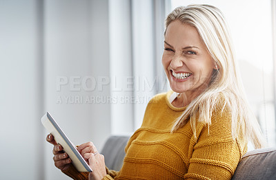 Buy stock photo Portrait of an attractive mature woman using a digital tablet while relaxing on the sofa at home